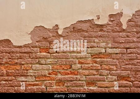 Old brick wall with peeling plaster, old background. Stock Photo