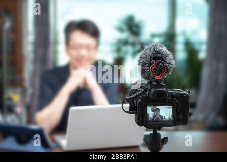 Online lecture concept. Asian middle-aged man giving online lectures at home. Blur background Stock Photo