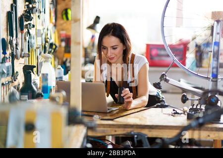 Confident young woman working in a bicycle repair shop Stock Photo
