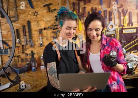 Two young women working in a bicycle repair shop Stock Photo