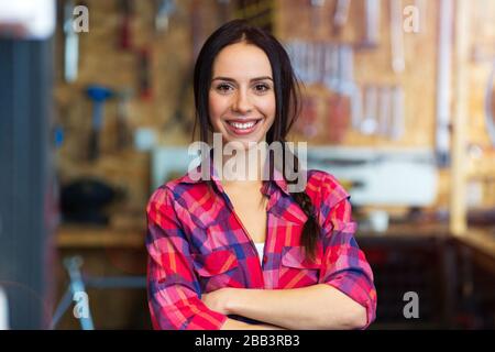Confident young woman working in a bicycle repair shop Stock Photo