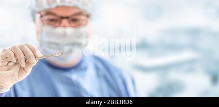 Doctor surgeon specialist with scalpel. In the background blurred the interior of the operating room. Stock Photo