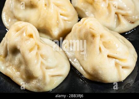 Manti (type of dumpling in turkic cuisine) oiled with butter close-up on black plate Stock Photo