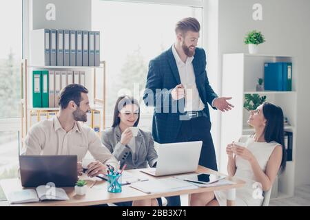 Happy excited colleagues in smart clothes are having nice conversation during the break in office at modern work place, drinking coffee and sharing Stock Photo