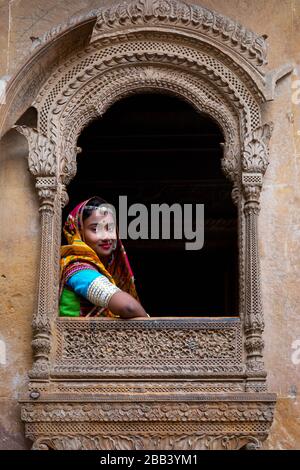 Portrait of a girl looking out of a window from an old haveli, Jaisalmer, Rajasthan, India Stock Photo