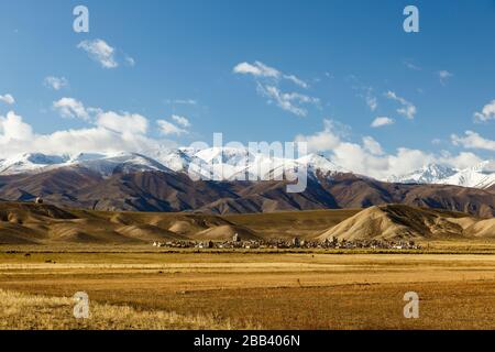 Cemetery in Kyrgyzstan at the foot of snow-capped mountains. Stock Photo