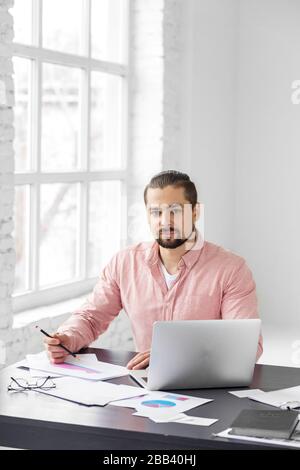 Young entrepreneur is working on a new project. A man with a beard. Concept for business, corporation, work and making big money. Stock Photo