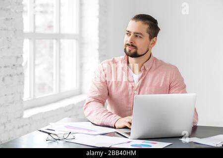 Young adult man working on the implementation of the plan. A man with a beard. Concept for business, corporation, work and making big money. Stock Photo