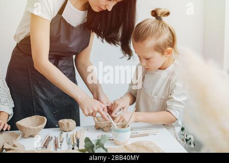 Close-up picture, master potter in an apron and a blond boy with long hair 7 years old, for a ceramics class Stock Photo