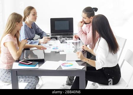 A group of colleagues discussing a creative project at work. The concept of entrepreneurs, success, making money and work. Stock Photo