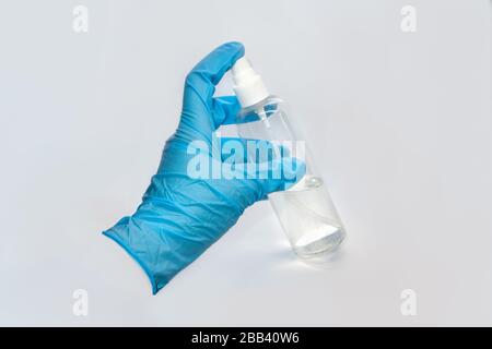 Spray disinfect liquid, hand in blue glove on white background. Sanitize spray water drops. Prevent virus illness spread in air aerosol. Clean hands c Stock Photo