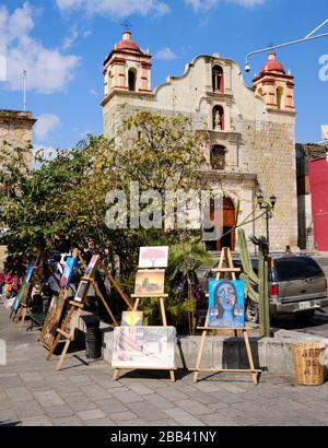 Artist displaying their art work for sale in Jardín Antonia Labastida with Iglesia Sangre De Cristo in background, in Oaxaca, Mexico Stock Photo