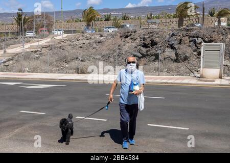 Man with his dog and wearing a mask during the coronavirus lockdown,  Playa San Juan, Tenerife, Canary Islands, Spain. Stock Photo