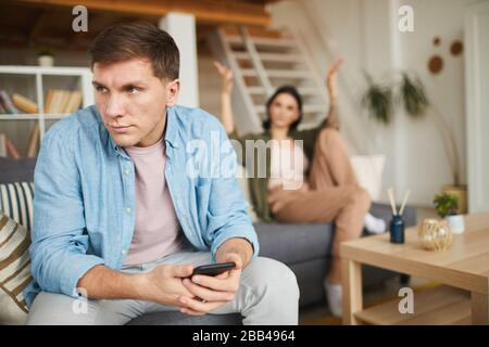 Portrait of modern couple fighting at home, focus on frustrated man in foreground, copy space Stock Photo