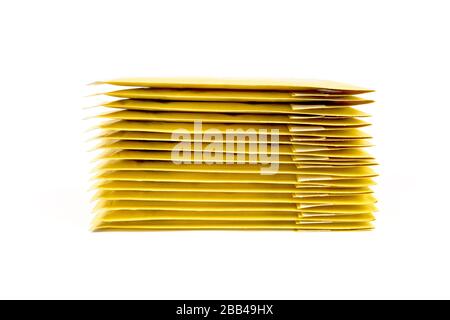 Stack of fifteen yellow bubble envelopes isolated on white, side view. Stock Photo