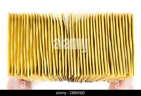 Huge stack of yellow mailing envelopes in hands, top view, isolated on white. Stock Photo