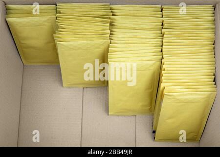 Four ascending rows of bubble envelopes inside a big cardboard box. Stock Photo