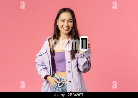 Online lifestyle, people and beauty concept. Portrait of modern stylish hipster girl, korean female showing you mobile phone display, recommend app or Stock Photo