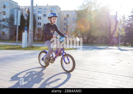 Boy child kid cycling biking riding bike wearing safety helmet, Sopron, Hungary Stock Photo