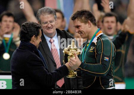 French President Nicolas Sarkozy (left) presents the winning captain John Smit (South Africa, captain, right) with the Webb Ellis Trophy. Watched by i Stock Photo