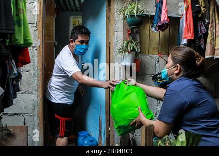 Quezon City. 30th Mar, 2020. A resident receives a bag of relief goods during the distribution of aid from the local government at a slum area in Quezon City, the Philippines on March 30, 2020. Credit: Rouelle Umali/Xinhua/Alamy Live News Stock Photo