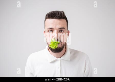 man holding a salad in his mouth. close up. isolated on white Stock Photo