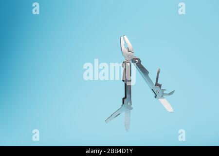The multitool multi-function tool hovers on a blue background. The concept of an expanded multi-tool with free space. Stock Photo