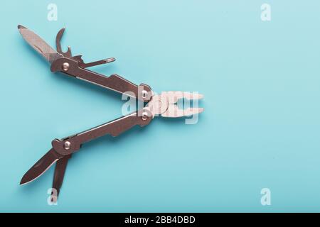 The multitool multi-function tool hovers on a blue background. The concept of an expanded multi-tool with free space. Stock Photo