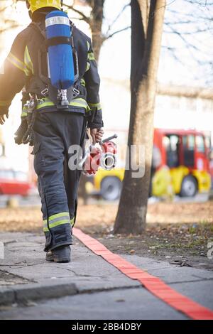 Fireman in uniform in front of fire truck going to rescue and protect. Emergancy , danger, servise concept. Stock Photo