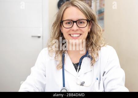 Confident female doctor posing smiling in her office . Stock Photo