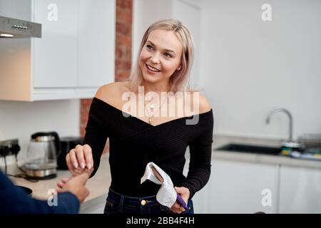 A mixed race couple share a bar of chocolate in the kitchen of their apartment Stock Photo