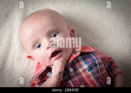 Surprised baby boy with big blue eyes looking directly at camera Stock Photo