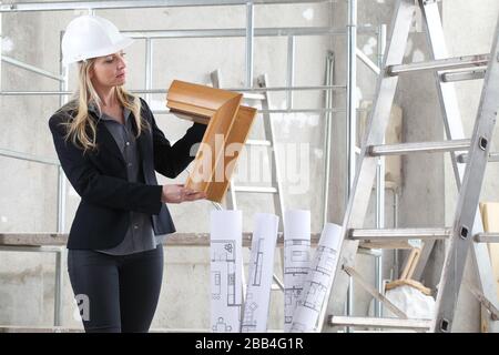 woman architect or construction interior designer with wooden windows cutaway inside a building site with ladder and scaffolding in the background Stock Photo