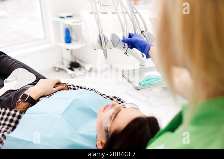 Dentist takes a drill in his hand to begin dental treatment for a young girl Stock Photo