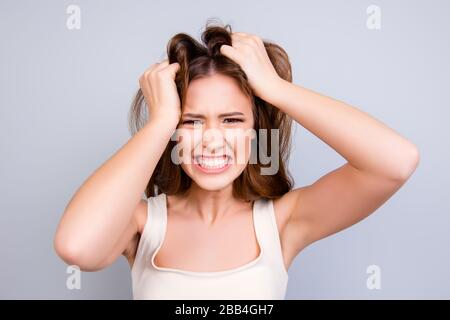Going crazy and insane. Close up portrait of shouting stressed young girl, messing her hair on pure light background Stock Photo
