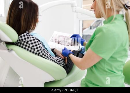 Dental clinic doctor shows a panoramic x-ray picture to his patient. Doctor explains to her patient the condition of her teeth Stock Photo