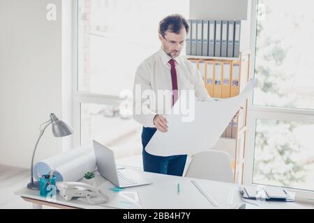 Concentrated specialist is holding scheme and looking at the project. He is focused on ideas Stock Photo