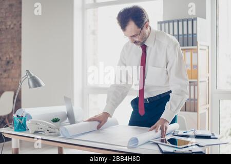 Close up photo of focused businessman working with scheme. He is standing by the table, studying the details of project Stock Photo