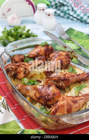 Baked chicken drumsticks with zucchini and potatoes in a glass form, Closeup Stock Photo