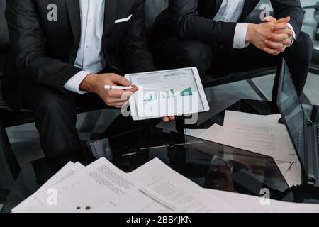 Close up businessman consulting client, holding document with graphs and diagram, mentor explaining business strategy to trainee, partners discussing Stock Photo