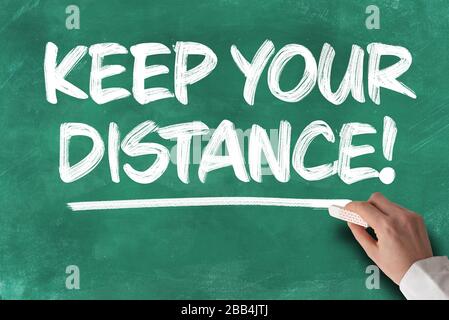text KEEP YOUR DISTANCE written on green chalkboard, social distancing concept during covid-19 coronavirus pandemic Stock Photo