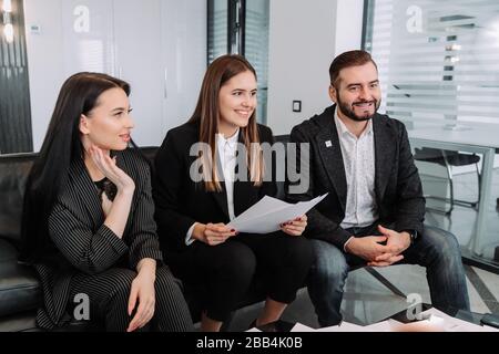 Business people discussing income charts and graphs during team meeting in modern office. Young colleagues sitting and analyzing financial reports. Co Stock Photo