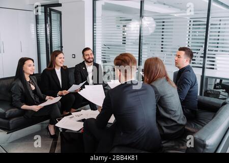 Teamwork. team discussing something and smiling while sitting at the office table Stock Photo