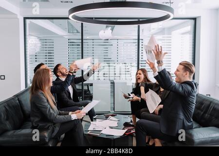 Happy overjoyed business team people staff group throwing tossing papers up in office celebrate corporate success. freedom at party enjoy victory danc Stock Photo