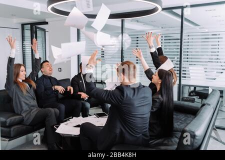 Happy overjoyed business team people staff group throwing tossing papers up in office celebrate corporate success. freedom at party enjoy victory danc Stock Photo