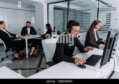 A technical support operator with a hands-free headset is talking to a customer in a call center. Stock Photo