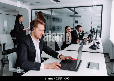 Smiling call center employees sit in line with a headset Stock Photo