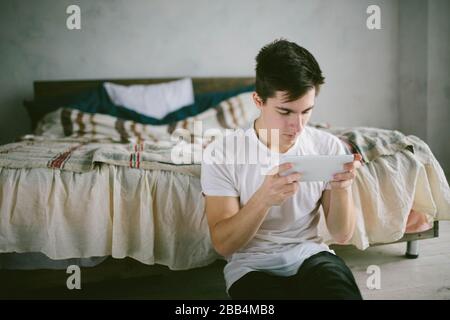 handsome man surfing on tablet. Guy talking with friends, video conference, skype, tablet. The young student scrolls social networks Stock Photo