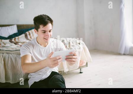 handsome man surfing on tablet. Guy talking with friends, video conference, skype, tablet. The young student scrolls social networks Stock Photo