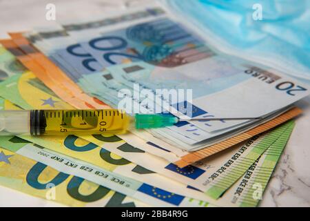 cost of coronavirus breakdown in europe Euro banknotes and vaccine Stock Photo